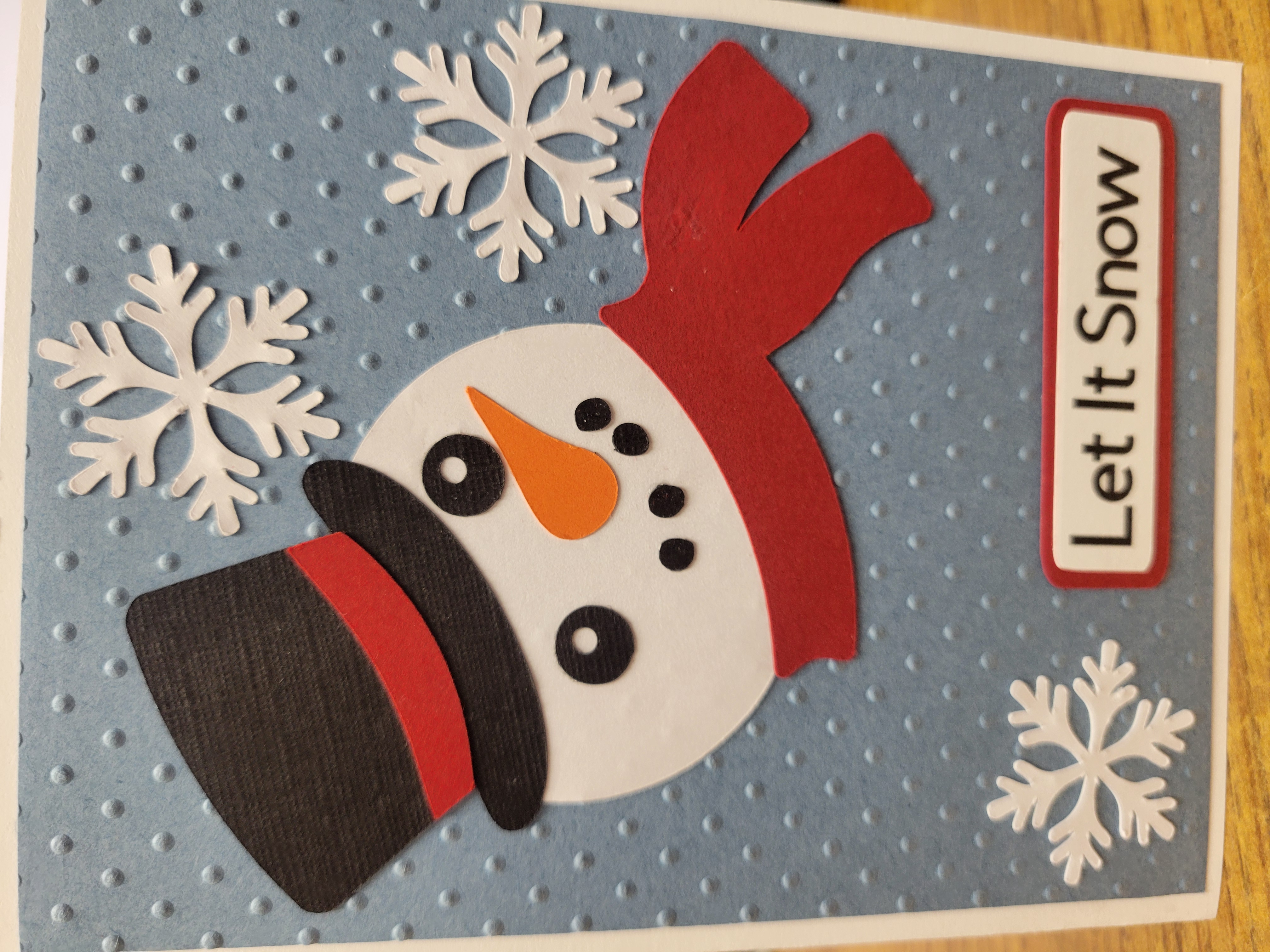 Christmas Card with blue background, snowman head and "Let It Snow"